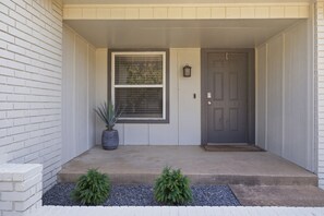 A front entrance with a grey door, a potted plant, and a small window.