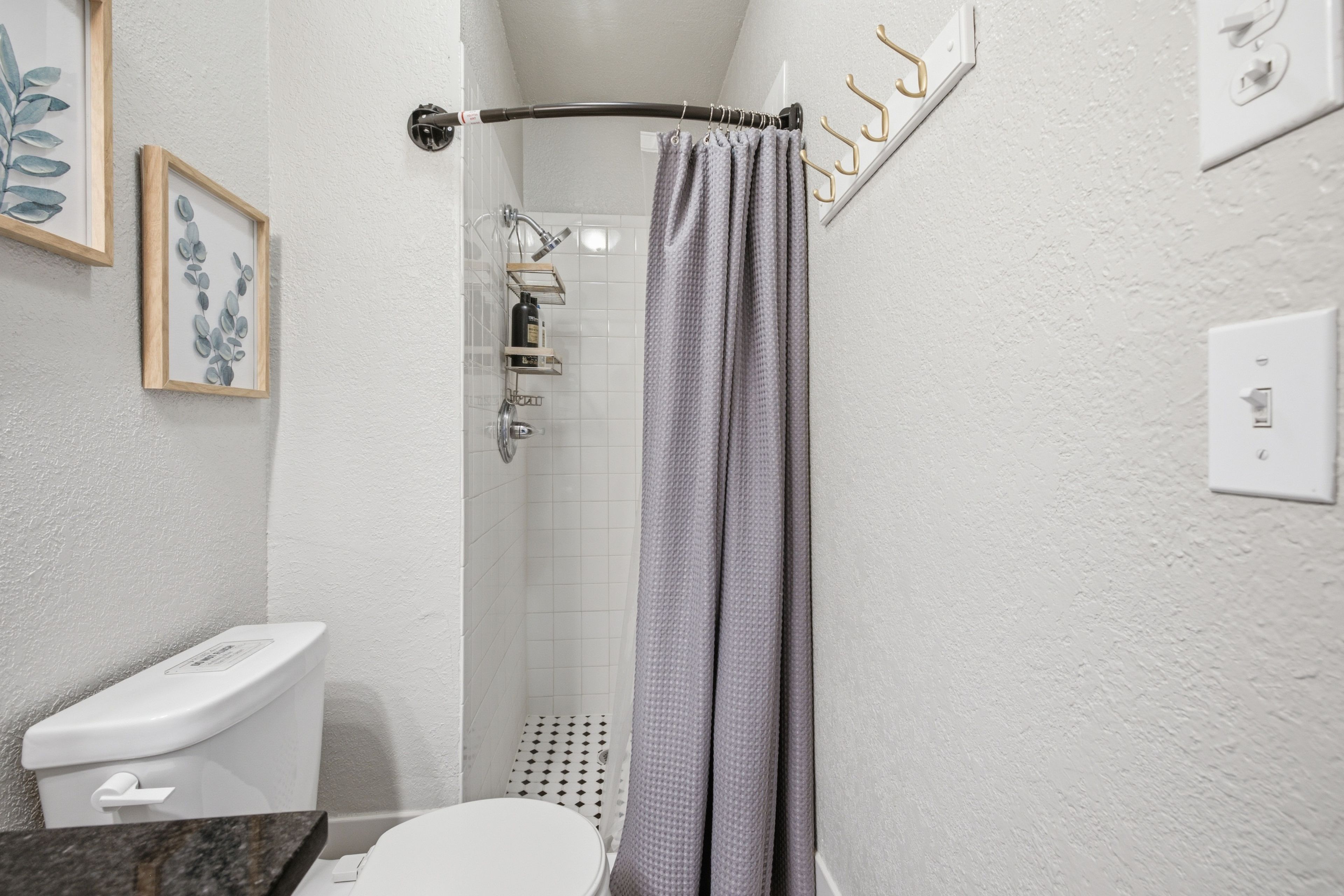 A bathroom with a shower, toilet, and a towel rack.