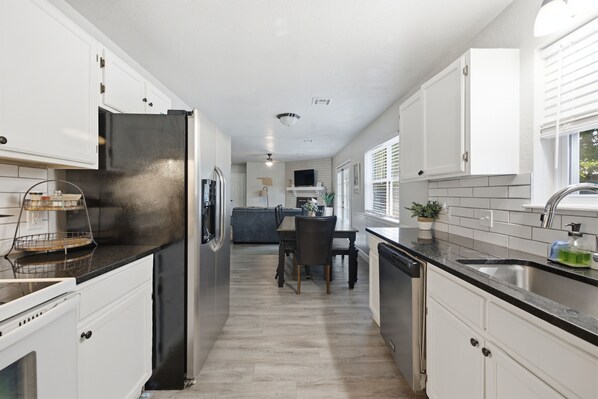 A modern kitchen with white cabinetry, a stainless steel refrigerator, and a dishwasher.