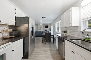 A modern kitchen with white cabinetry, a stainless steel refrigerator, and a dishwasher. - Cozy 3BR family retreat with a fenced backyard, patio, and everything you need for a comfortable stay in Broken Arrow. Pet friendly! (Broken Arrow)