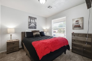 A bedroom with a bed, bedside tables, a window with blinds, a wall-mounted artwork, and a dresser. - Cozy 3BR family retreat with a fenced backyard, patio, and everything you need for a comfortable stay in Broken Arrow. Pet friendly! (Broken Arrow)