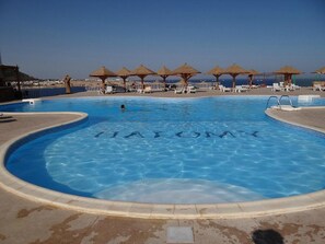 A swimming pool with the words "FAT CAT" written in the water, surrounded by lounge chairs and umbrellas. - Grand Halomy resort (Sharm El Sheikh)