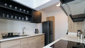 Eine moderne Küche mit eingebautem Geschirrspüler, einer Kaffeemaschine und einem schwarzen Kühlschrank.