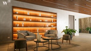 Eine moderne Lobby mit einer Wandverkleidung aus Holz, bequemen Sitzgelegenheiten und einer großen Topfpflanze.