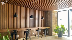 Ein modernes Interieur mit Holzbalkendecke, einer langen Theke mit Barhocker und einer großen Topfpflanze.