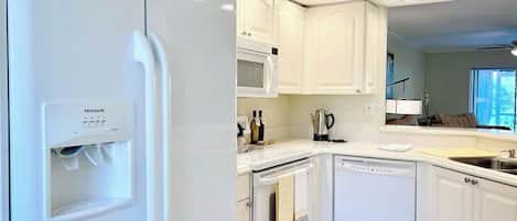Una cocina moderna con armarios blancos, microondas integrado, horno y lavavajillas.