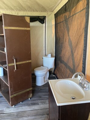 Un bagno piccolo con un water bianco, un lavandino con rubinetto cromato e una porta marrone.