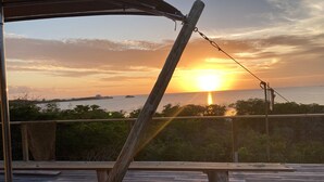 Eine Holzterrasse mit Blick auf den Sonnenuntergang über dem Meer.