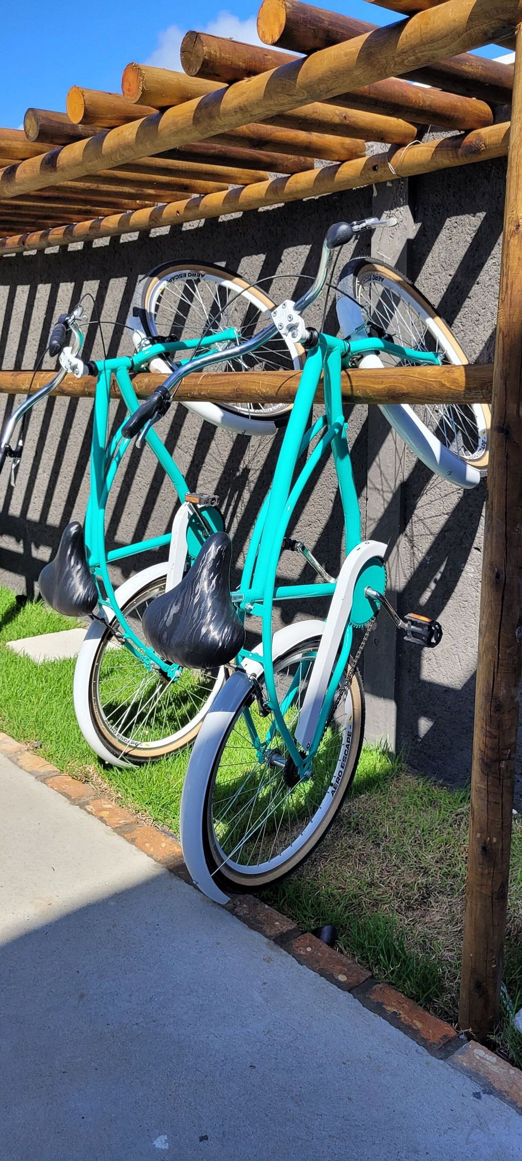 Uma bicicleta turquesa encostada a uma cerca de madeira com corrimão de metal.