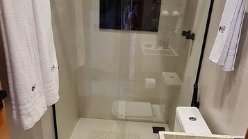 A modern bathroom with a glass-enclosed shower, a toilet, and a sink area.