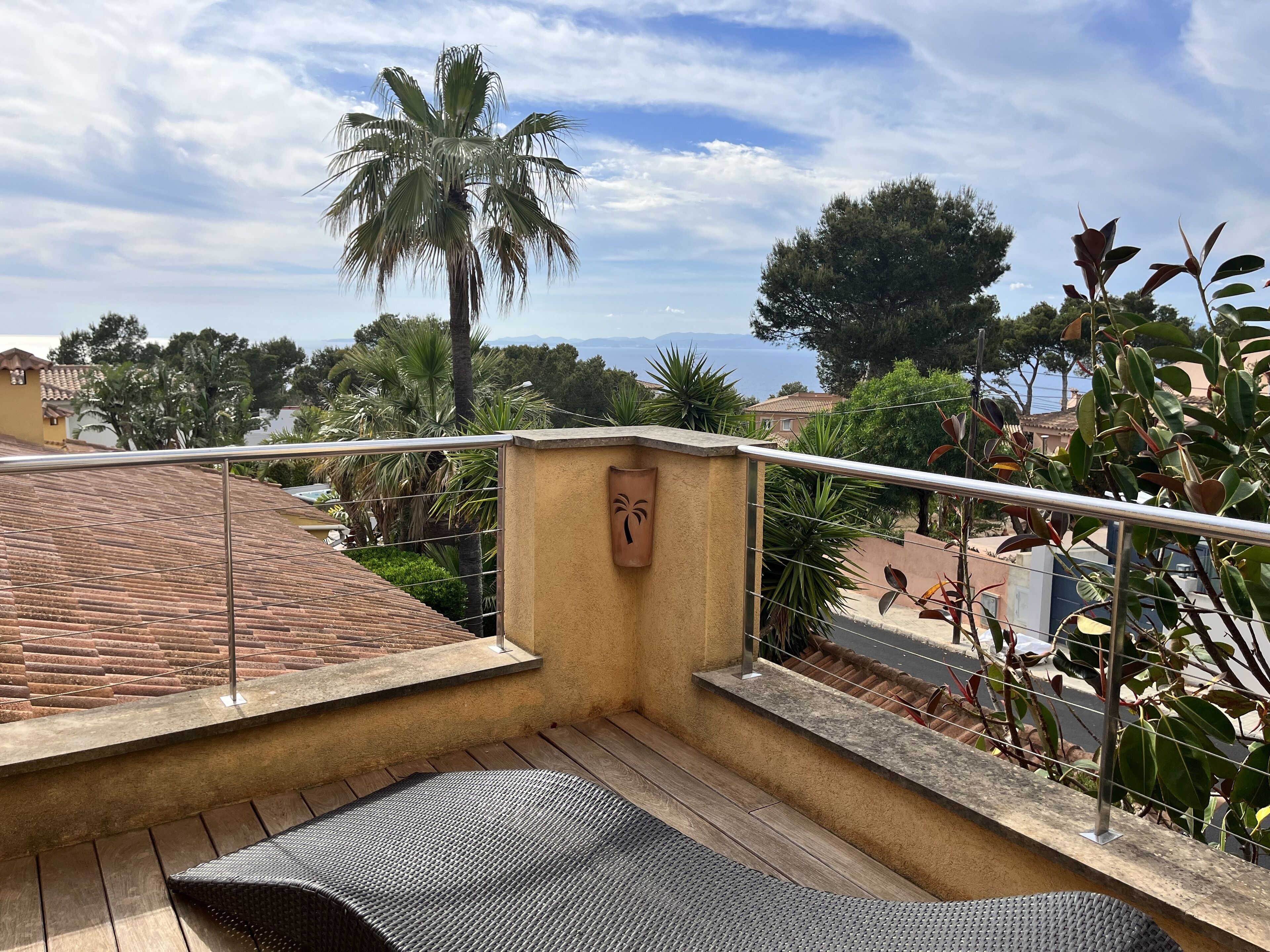 A balcony with a view of palm trees and a distant landscape.
