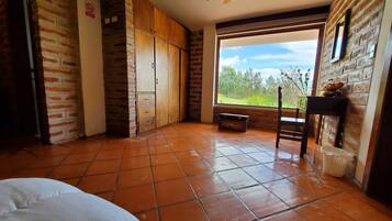 Una habitación con un ventanal grande, un armario de madera y suelo de baldosas.
