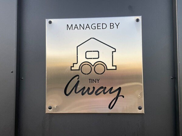 A metallic sign with a house icon and the text 'MANAGED BY TINY Away.'