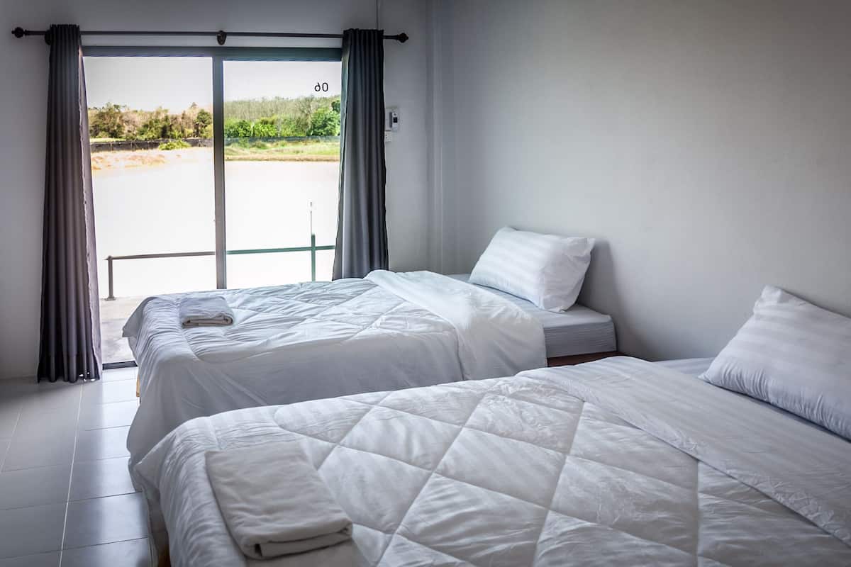 Une chambre d’hôtel avec deux lits, une porte-fenêtre coulissante donnant sur l’extérieur et une vue sur la plage.