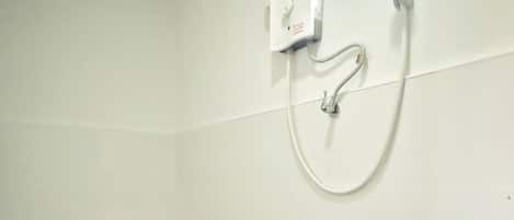 A bathroom with a toilet, a shower, and a wall-mounted control panel.