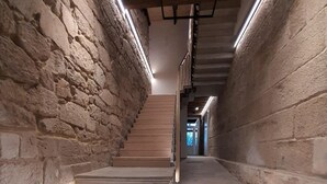 A staircase with stone walls and wooden steps, leading to a door at the top. - Acouga Hotel Boutique (Celanova)