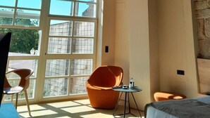 A room with a sloped wooden ceiling, large windows, and a modern orange chair. - Acouga Hotel Boutique (Celanova)