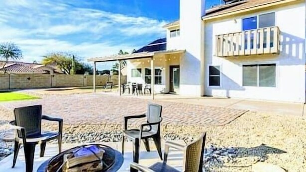 Een modern huis met een terras, buitenmeubels en een vuurkorf.