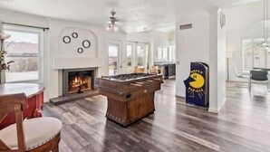 Een ruime woonkamer met een open haard, een houten entertainmentcentrum en een groot raam.