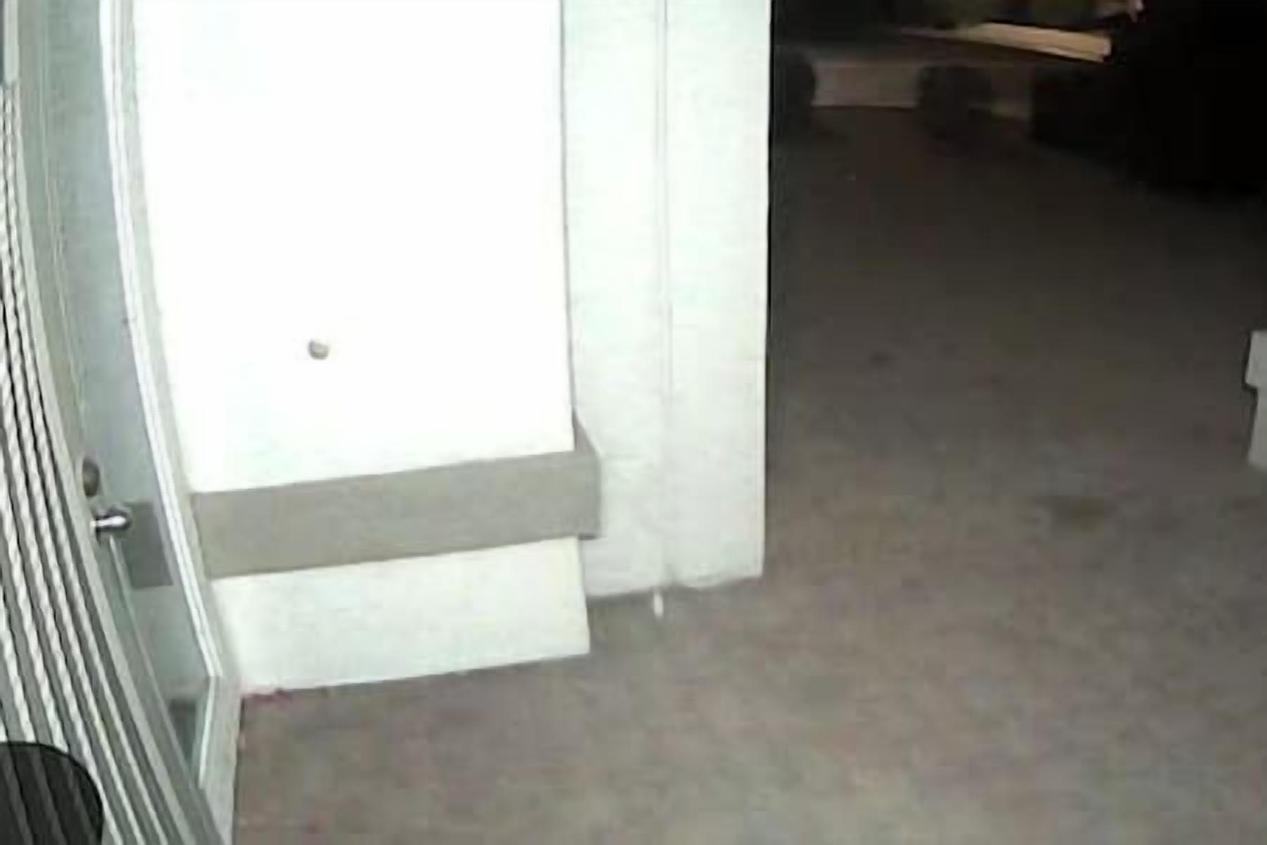 A room with a white door, a grey carpet, and a visible step leading to the door.