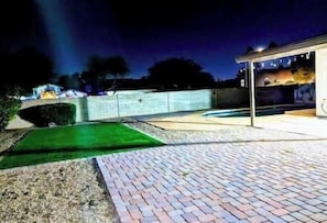 A paved patio area with a brick walkway and a green lawn. - Luxury Home in Phoenix Peoria for 16 Guests & Pool (Peoria)