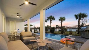 A covered outdoor area with a pool, lounge chairs, and a grill. - Perfect Paradise | All New, All Yours Beach Oasis w/ Pool, Theater, Karaoke Rm (Melbourne Beach)