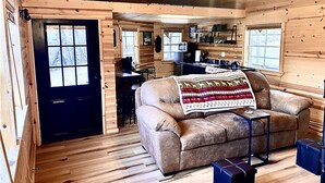 A cozy cabin interior with a sofa, a coffee table, and a dining area.