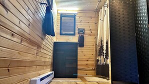 A wooden interior with a door, a small window, and a wall-mounted light fixture.