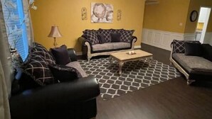 Een woonkamer met een bank, fauteuils, een salontafel en een kroonluchter.
