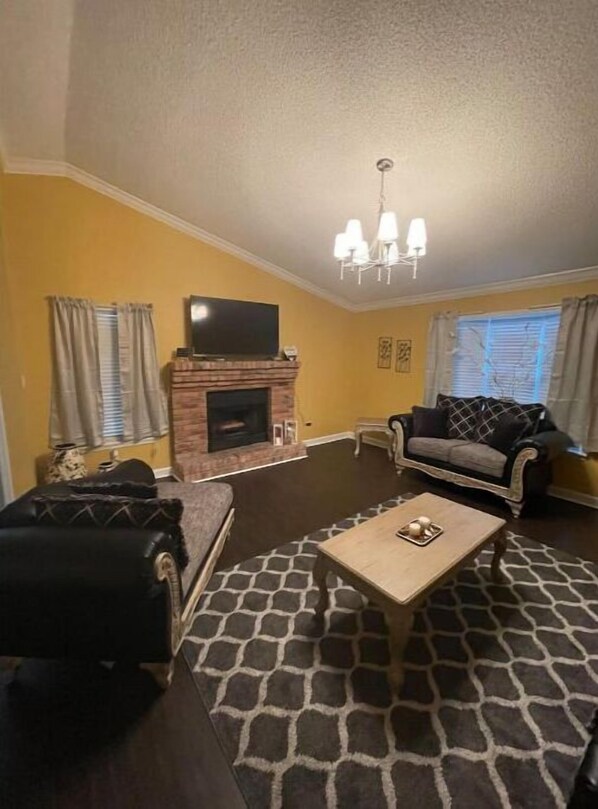 Un salon avec une cheminée, un canapé, une table basse et un téléviseur.