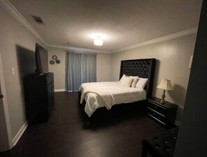 Une chambre d’hôtel avec un lit, une commode, une lampe et un téléviseur.