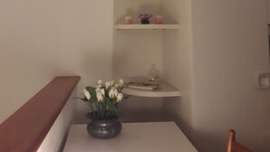 A corner of a room with a white table, a vase with white flowers, and a white shelf with decorative items. - EMY & LU HOLIDAY HOME UPPER TOWN (Bergamo)