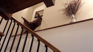 A wooden staircase with a handrail, a wall-mounted vase with dried plants, and a framed picture. - EMY & LU HOLIDAY HOME UPPER TOWN (Bergamo)