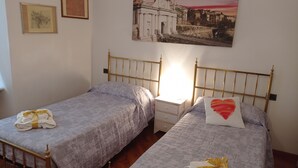 A hotel room with two single beds, a bedside table with a lamp, and a wall-mounted painting. - EMY & LU HOLIDAY HOME UPPER TOWN (Bergamo)