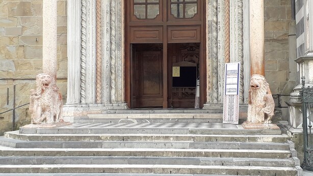 A grand entrance with a wooden door, flanked by two lion statues, leading to a set of stone steps. - EMY & LU HOLIDAY HOME UPPER TOWN (Bergamo)