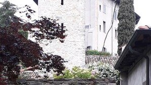 A stone wall with flowering plants and a building in the background. - EMY & LU HOLIDAY HOME UPPER TOWN (Bergamo)