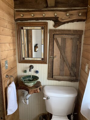 Une salle de bain rustique avec un meuble-lavabo en bois, un grand miroir et des toilettes blanches.