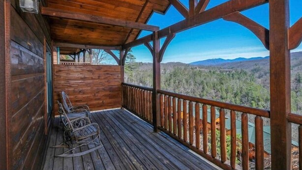 A wooden deck with a view of a forest and mountains.