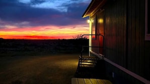 A building with a porch and a view of a sunset.