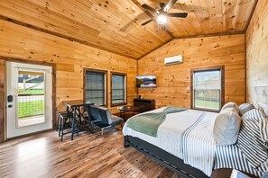 Een houten slaapkamer met een bed, een bureau, een stoel en een televisie.