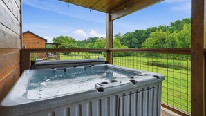 A hot tub in a wooden cabin with a view of a green landscape. - Romantic Smoky Mountain Cabin | Hot Tub | Pet-Friendly (Sevierville)