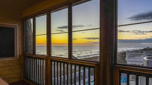 Ein Zimmer mit großen Fenstern mit Blick auf Strand und Pool.