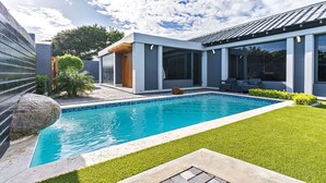 Een modern huis met een zwembad, een verzorgd gazon en een groot raam met uitzicht op het zwembad.