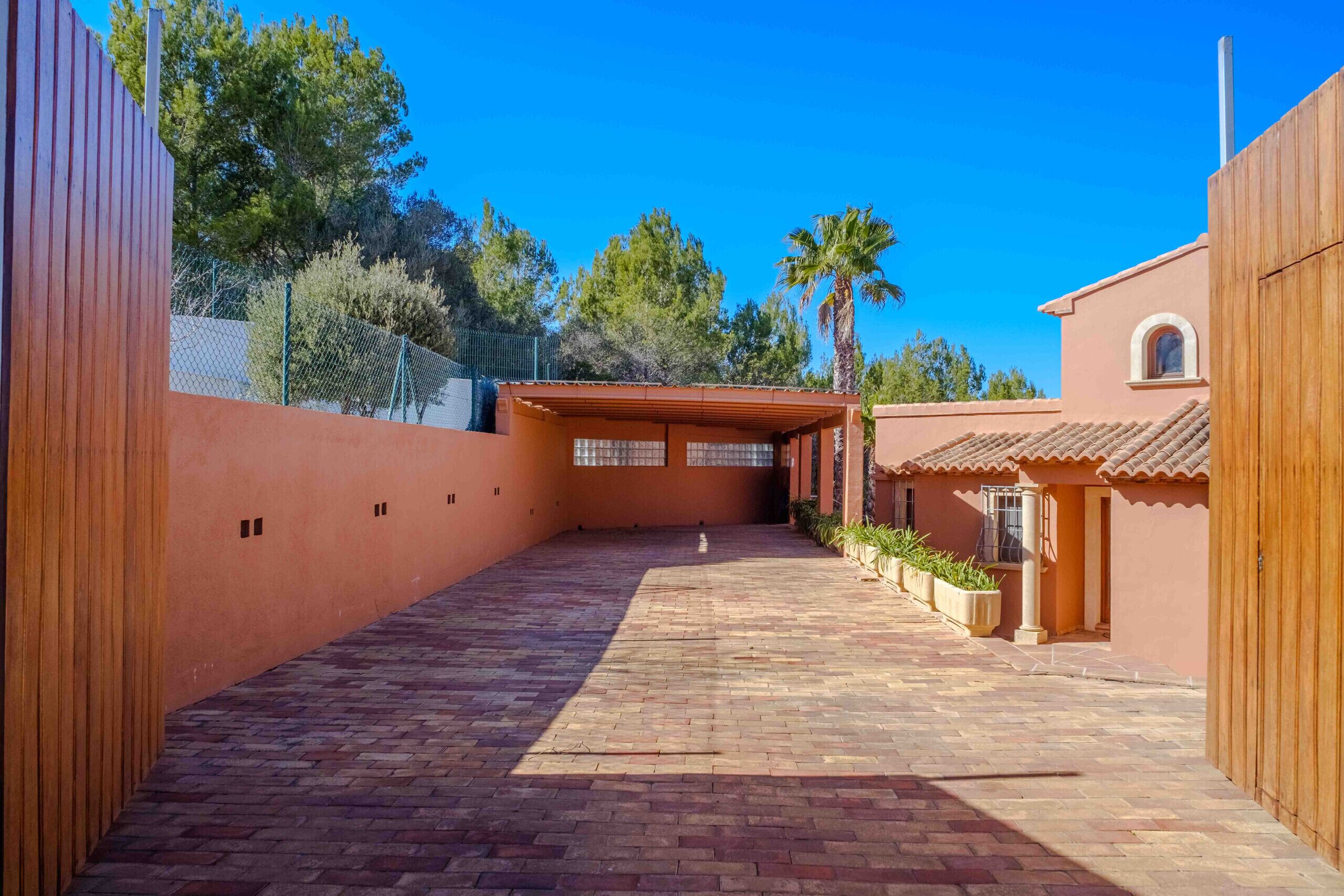 A courtyard with a brick pathway, a covered seating area, and a building with a tiled roof.