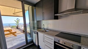 Una cocina moderna con un suelo de vidrio corredera que da a un balcón con vista al mar.