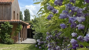 A wooden building with a tiled roof, a covered porch, and a pathway leading to the entrance. - Atypical villa "Cabane Oléron" with heated swimming pool (Saint-Trojan-les-Bains)