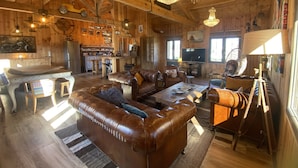 A rustic wooden interior with a leather sofa, dining table, and chandelier. - Atypical villa "Cabane Oléron" with heated swimming pool (Saint-Trojan-les-Bains)