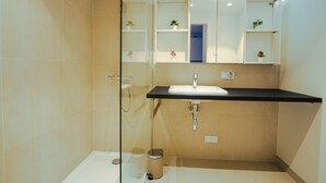 Un bany modern amb plat de dutxa de vidre, un lavabo amb taulell negre i un mirall sobre el lavabo.