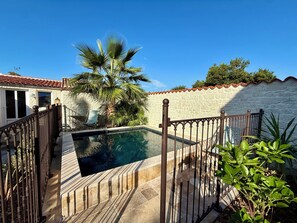 Una piscina con muro de piedra y valla metálica.