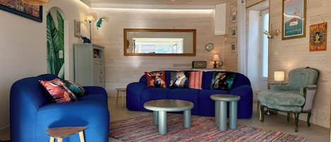 A living room with a blue sofa, a small round table, and a colorful rug.